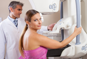 Woman undergoing mammography scan assisted by male doctor