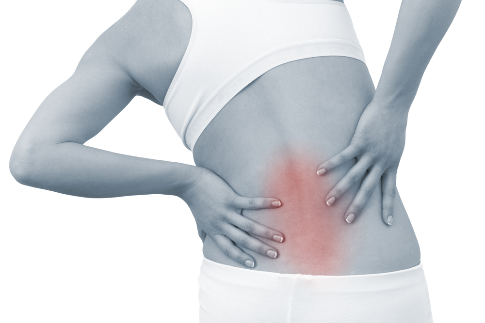 Schwarzweiß-Bild, in dem eine Frau ihren schmerzenden Rücken hält. Der schmerzende Rücken ist durch die rötliche Färbung gekennzeichnet.